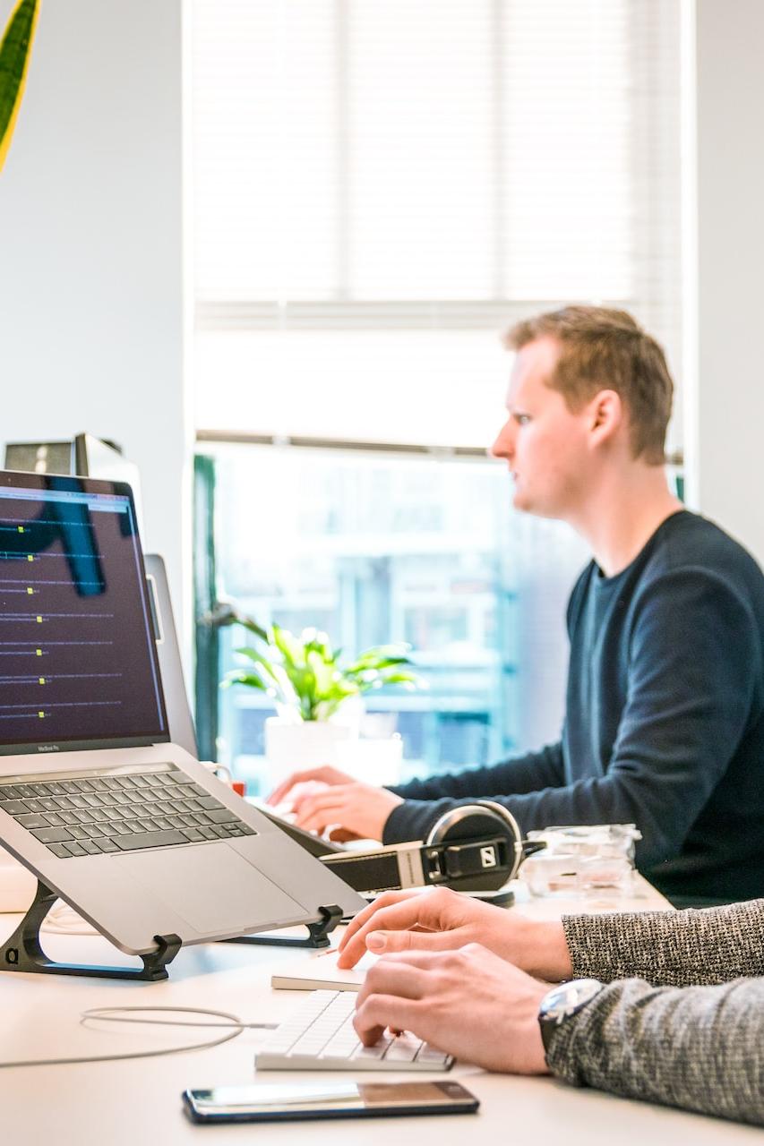 man sitting on chair wearing gray crew-neck long-sleeved shirt using Apple Magic Keyboard